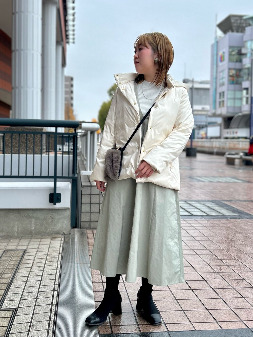 ホワイト系のダウンジャケット/コート、グレー系のワンピース、シルバー系のニット/セーターを着用したレディースの冬コーディネートの6枚目の写真