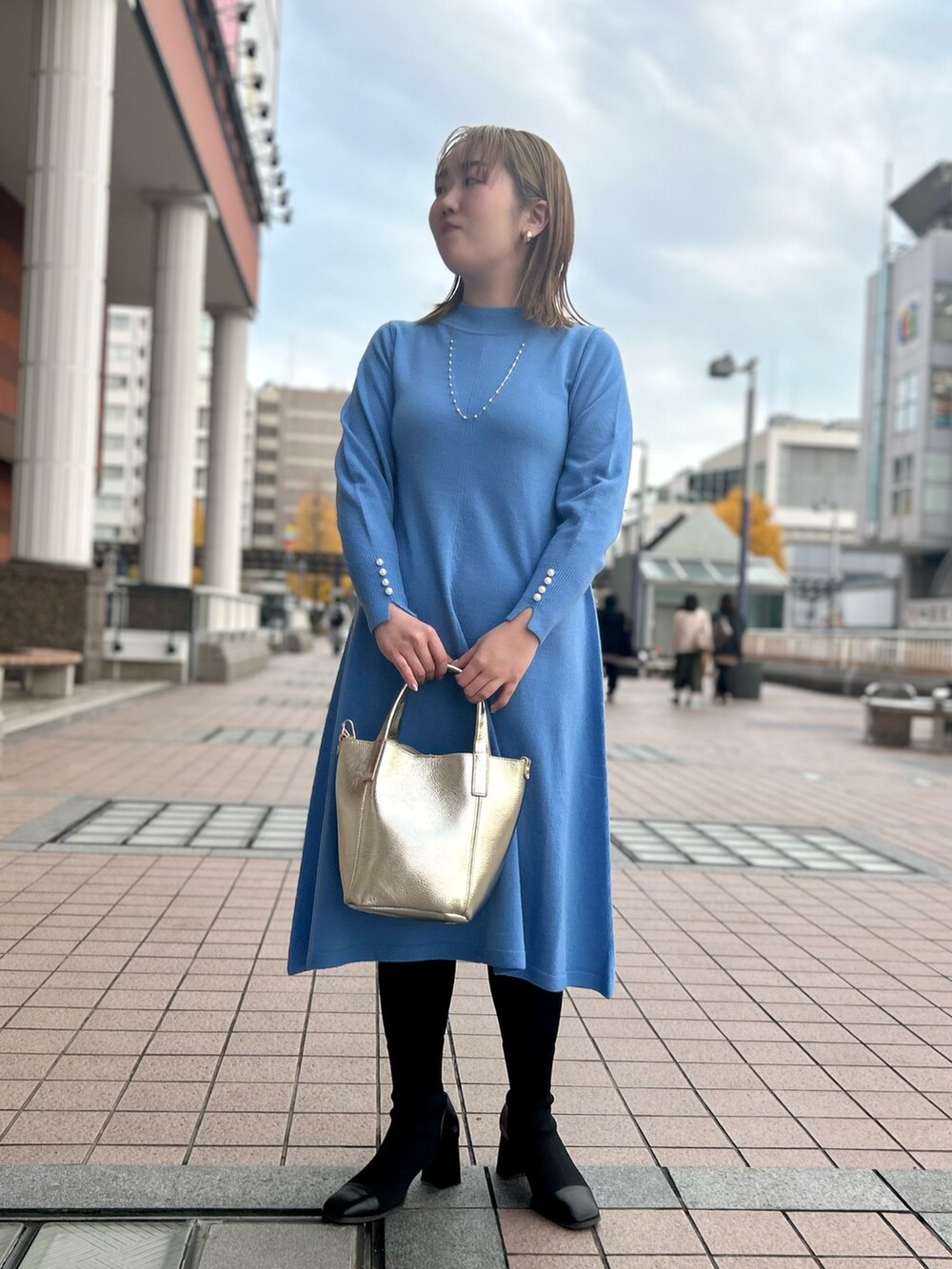 ブルー系のワンピース、ゴールド系のトートバッグ、ゴールド系のイヤリングを着用したレディースの冬コーディネートの9枚目の写真