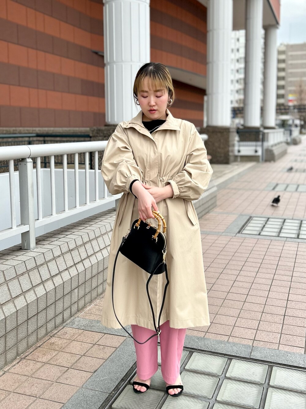 ベージュ系のその他アウター、ブラック系のニット/セーター、ピンク系のチノパンツを着用したレディースの春コーディネートの7枚目の写真