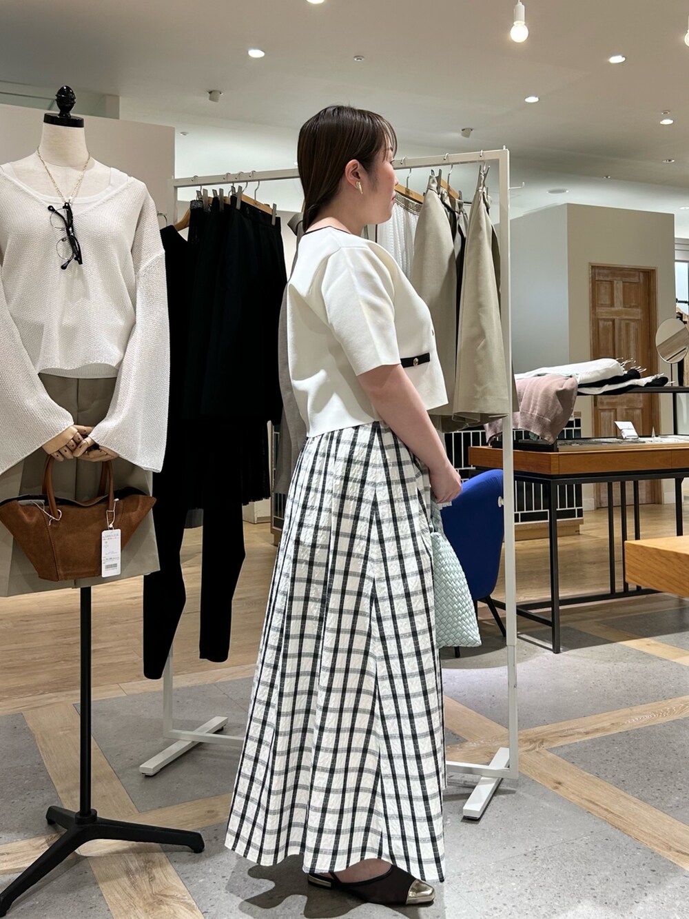 ホワイト系のノーカラージャケット、グリーン系のショルダーバッグ、ゴールド系のイヤリングを着用したレディースの夏コーディネートの4枚目の写真