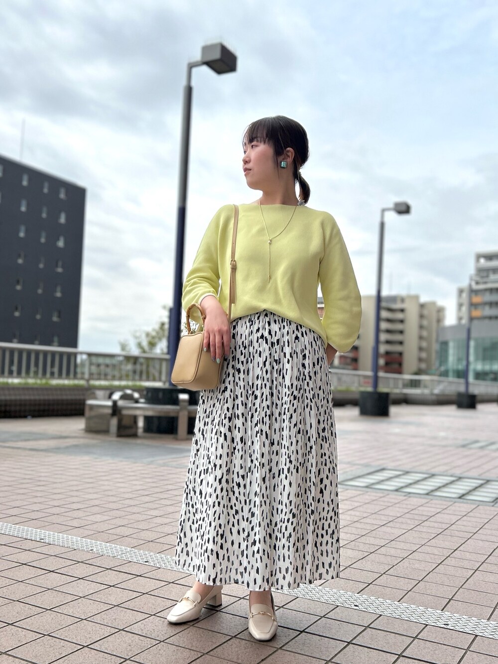 ホワイト系のスカート、ベージュ系のハンドバッグ、イエロー系のニット/セーターを着用したレディースの春コーディネートの7枚目の写真