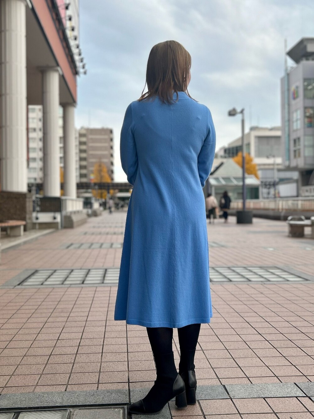 ブルー系のワンピース、ゴールド系のトートバッグ、ゴールド系のイヤリングを着用したレディースの冬コーディネートの4枚目の写真