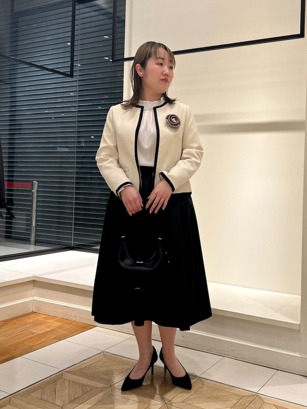 ホワイト系のノーカラージャケット、ホワイト系のシャツ/ブラウス、ブラック系のショルダーバッグを着用したレディースの冬コーディネートの6枚目の写真