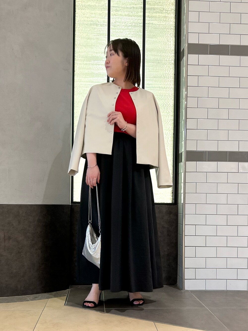 ベージュ系のブルゾン、レッド系のTシャツ/カットソー、ブラック系のスカートを着用したレディースの秋コーディネートの2枚目の写真