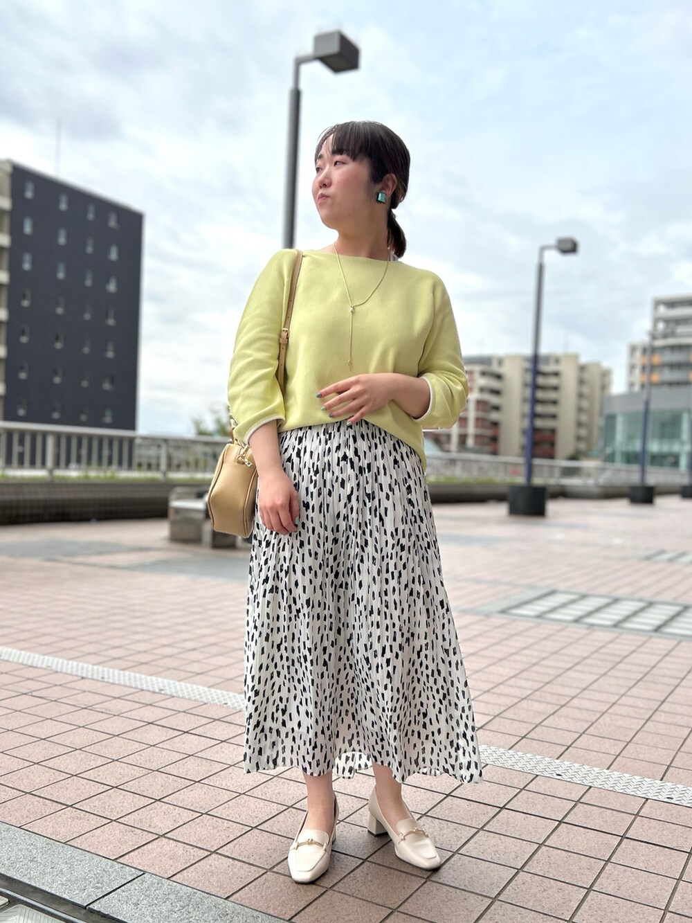 ホワイト系のスカート、ベージュ系のハンドバッグ、イエロー系のニット/セーターを着用したレディースの春コーディネートの9枚目の写真