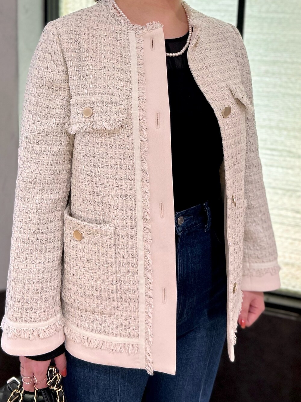 ホワイト系のノーカラージャケット、ブラック系のTシャツ/カットソー、ブルー系のデニムパンツを着用したレディースの夏コーディネートの6枚目の写真