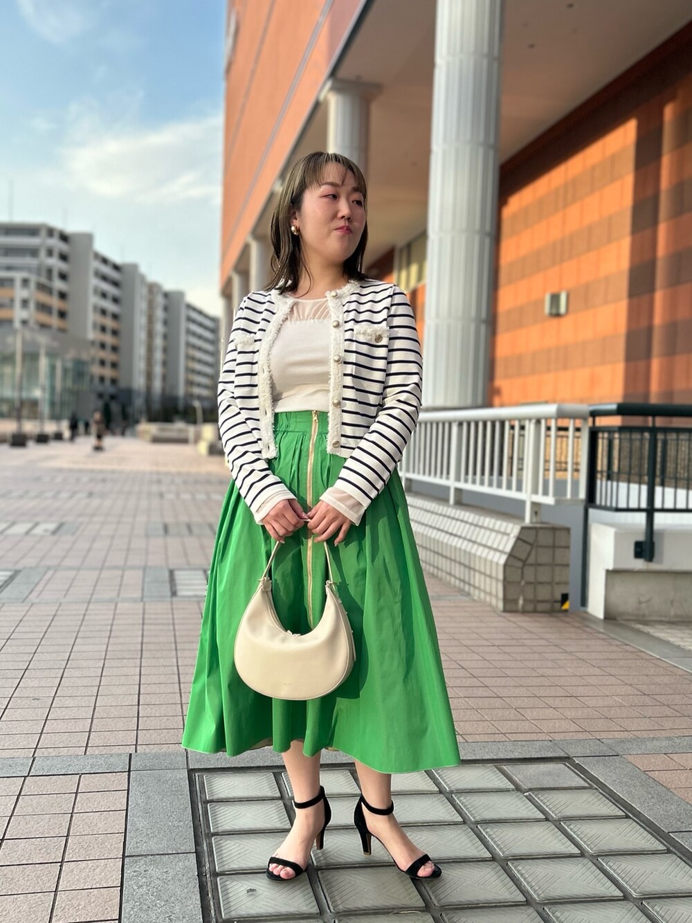 ホワイト系のカーディガン/ボレロ、グリーン系のスカート、ホワイト系のTシャツ/カットソーを着用したレディースの冬コーディネートの2枚目の写真