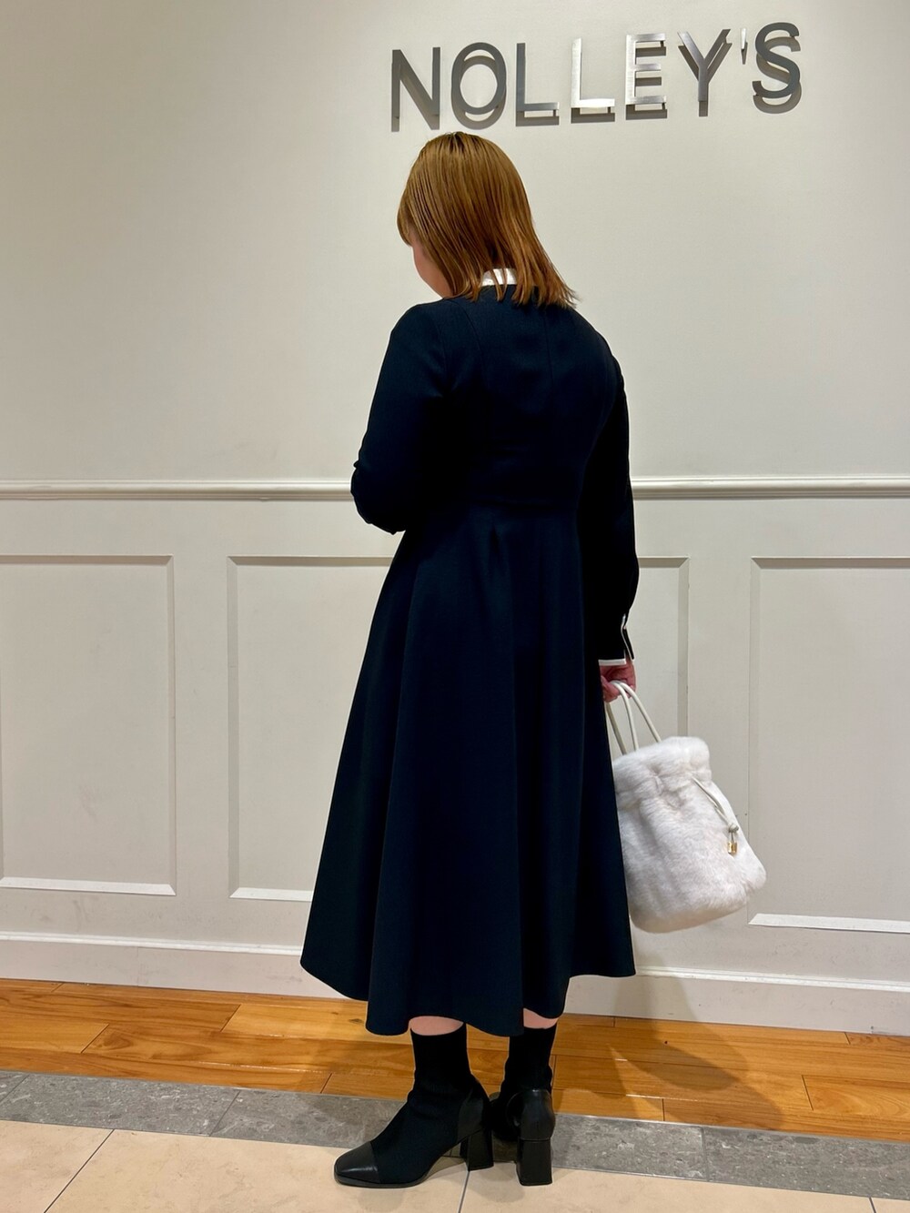 ブルー系のワンピース、ホワイト系のショルダーバッグ、ホワイト系のイヤリングを着用したレディースの冬コーディネートの4枚目の写真