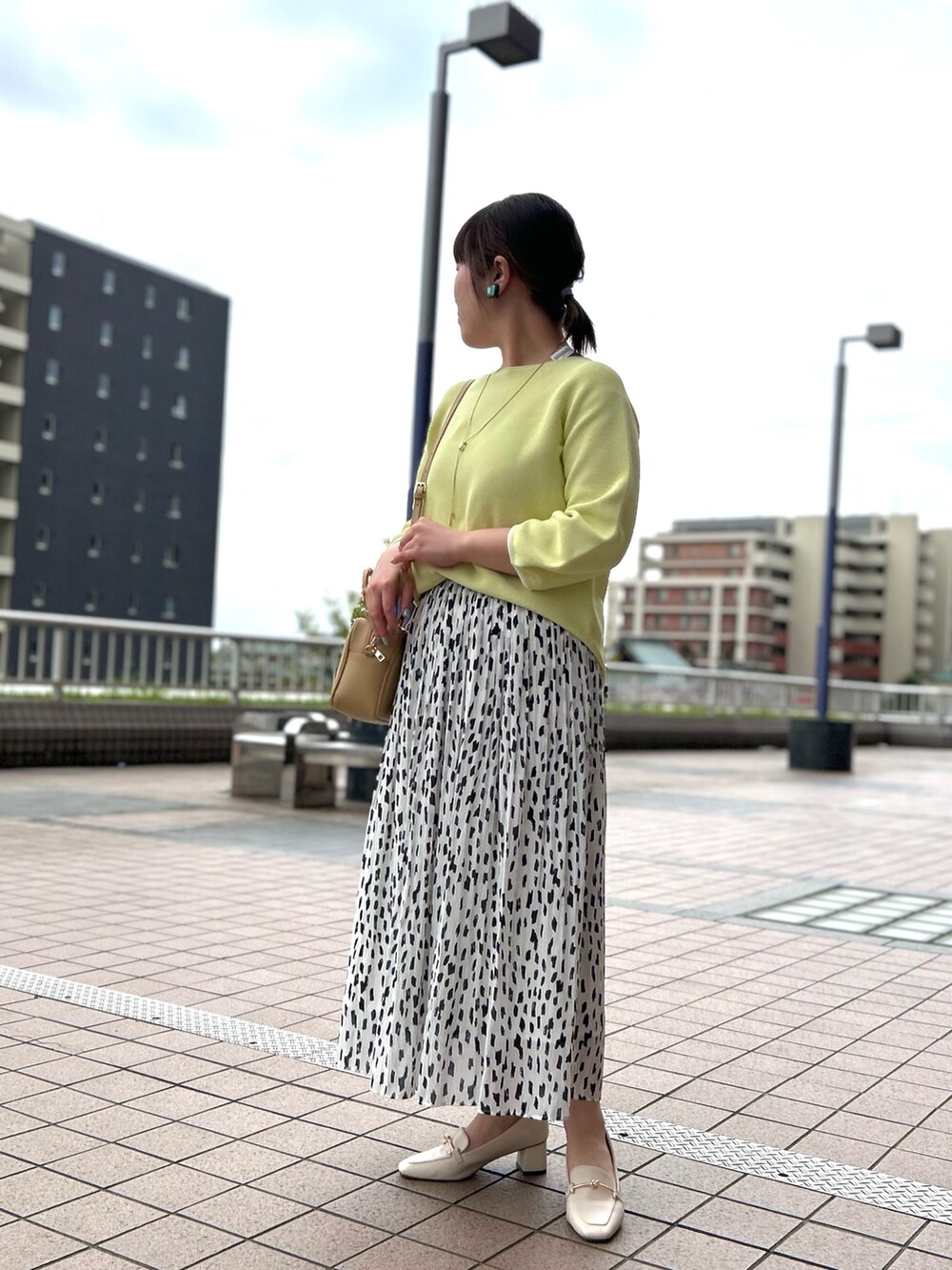 ホワイト系のスカート、ベージュ系のハンドバッグ、イエロー系のニット/セーターを着用したレディースの春コーディネートの2枚目の写真