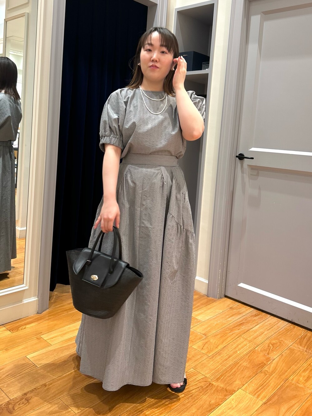 グレー系のシャツ/ブラウス、グレー系のスカート、ブラック系のかごバッグを着用したレディースの夏コーディネートの8枚目の写真