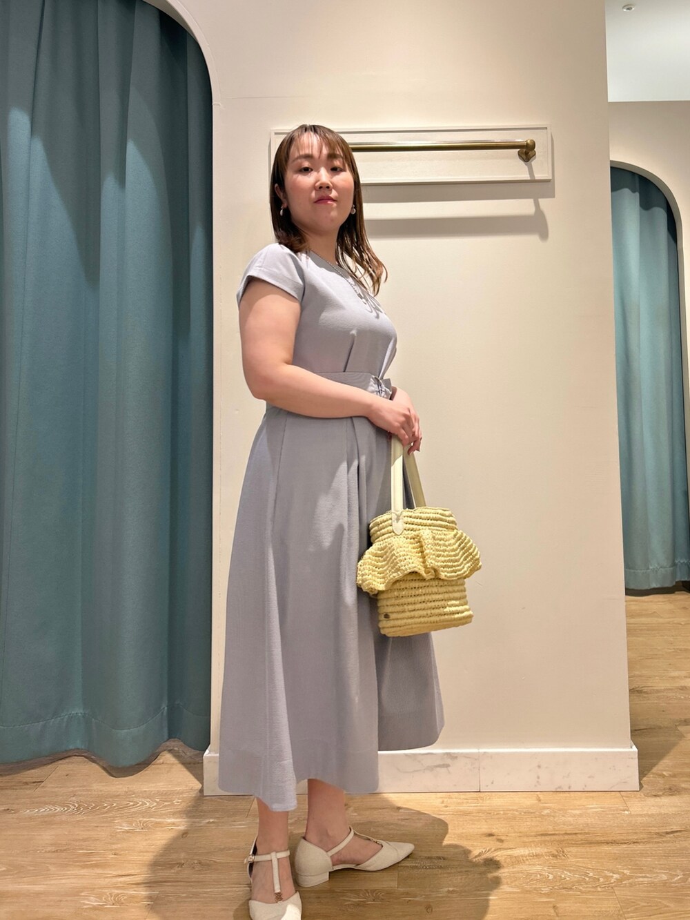 ブルー系のワンピース、ベージュ系のかごバッグ、シルバー系のネックレスを着用したレディースの夏コーディネートの3枚目の写真