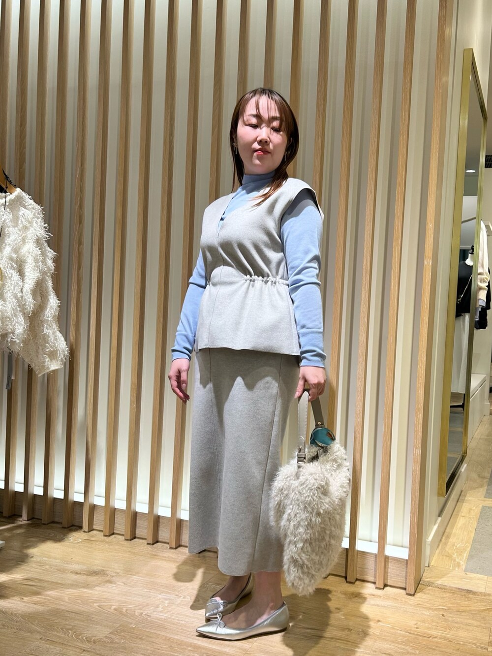 グレー系のベスト、グレー系のスカート、ブルー系のニット/セーターを着用したレディースの冬コーディネートの8枚目の写真