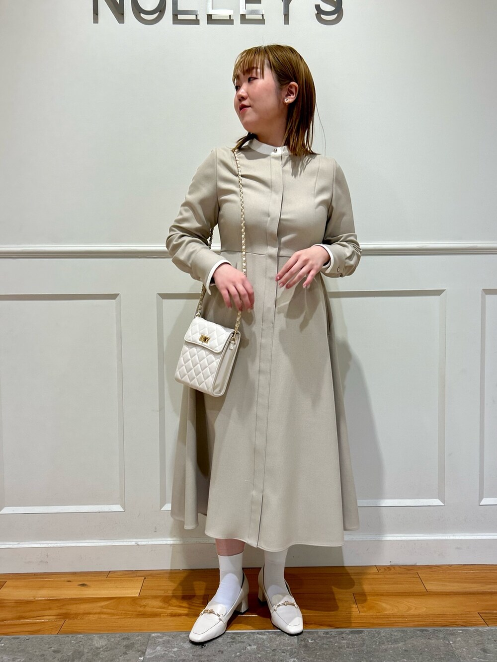 ベージュ系のワンピース、ホワイト系のショルダーバッグ、ホワイト系のイヤリングを着用したレディースの冬コーディネートの10枚目の写真