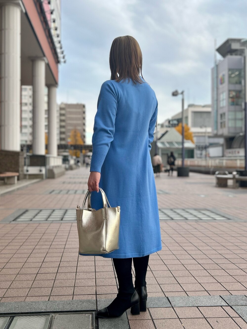ブルー系のワンピース、ゴールド系のトートバッグ、ゴールド系のイヤリングを着用したレディースの冬コーディネートの8枚目の写真