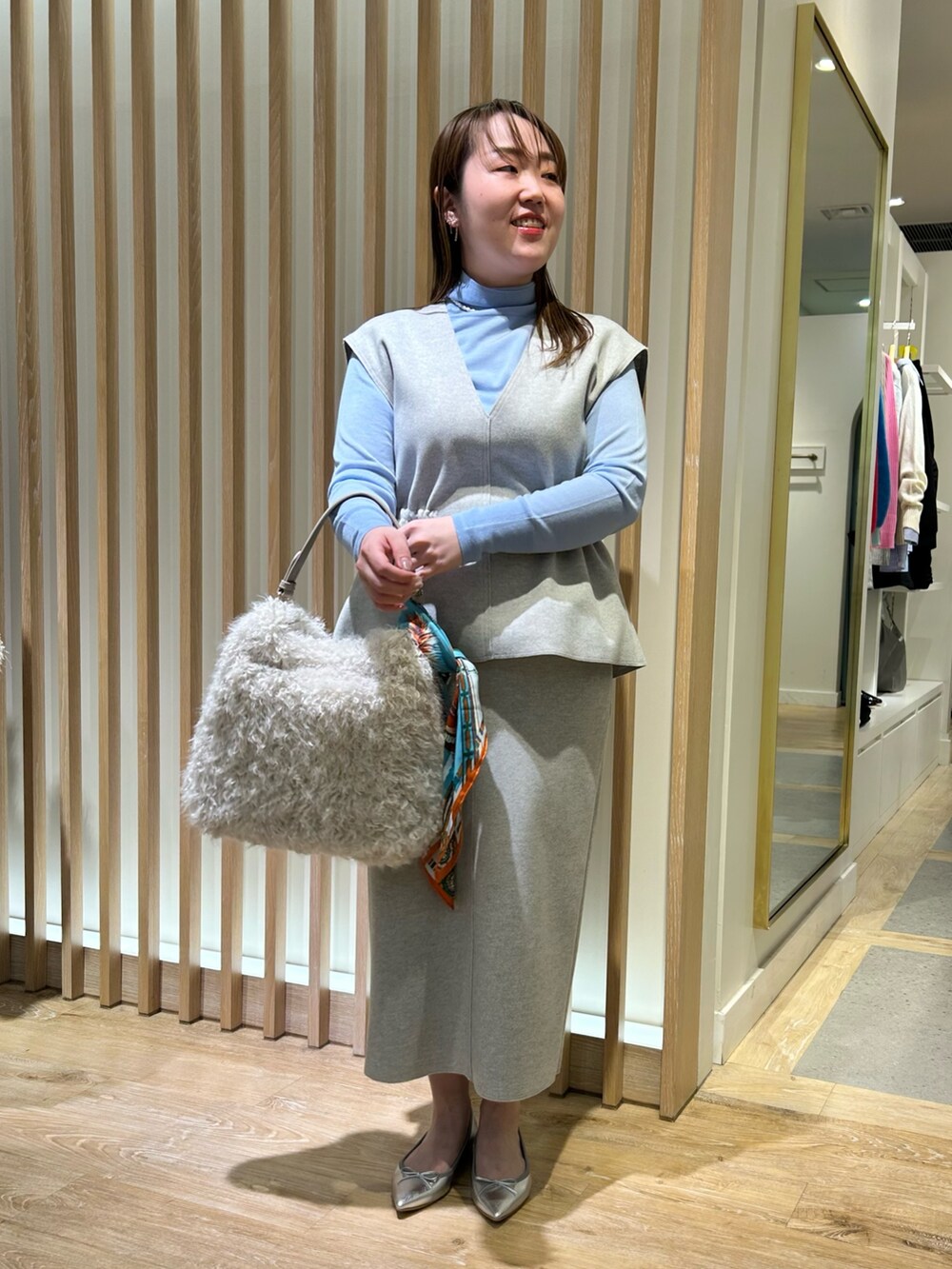 グレー系のベスト、グレー系のスカート、ブルー系のニット/セーターを着用したレディースの冬コーディネートの6枚目の写真