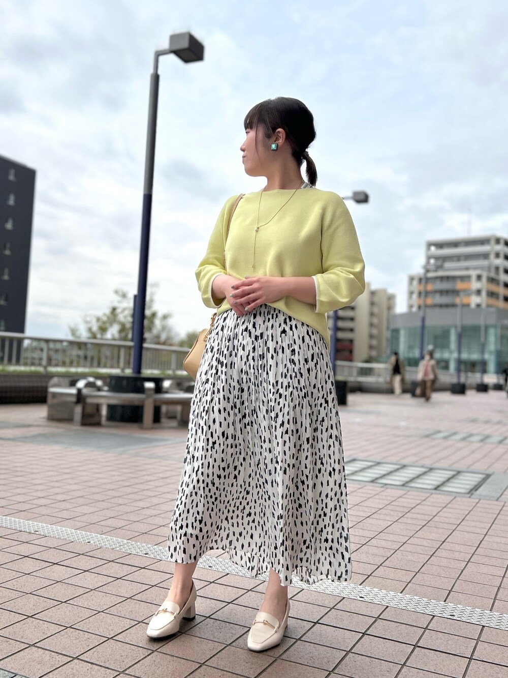 ホワイト系のスカート、ベージュ系のハンドバッグ、イエロー系のニット/セーターを着用したレディースの春コーディネートの6枚目の写真