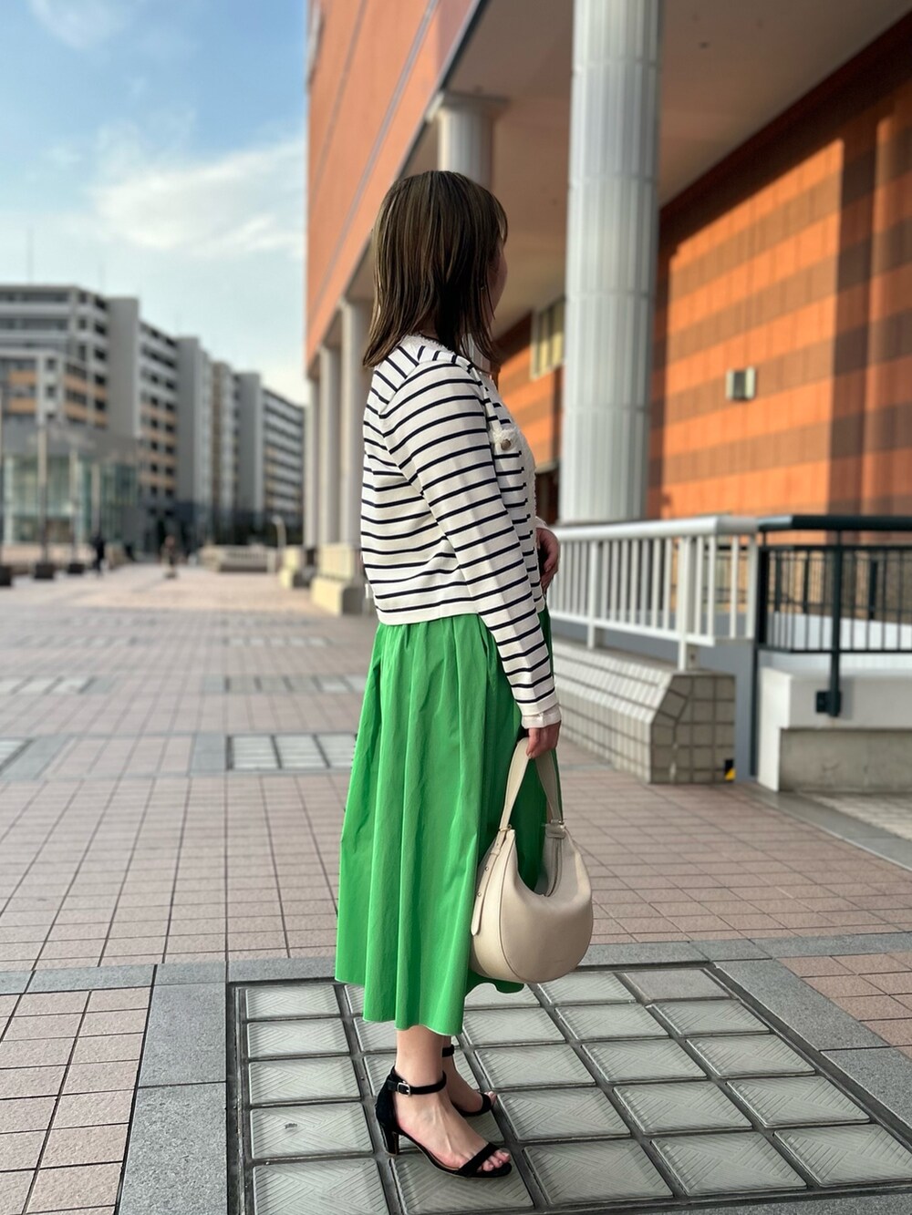 ホワイト系のカーディガン/ボレロ、グリーン系のスカート、ホワイト系のTシャツ/カットソーを着用したレディースの冬コーディネートの3枚目の写真