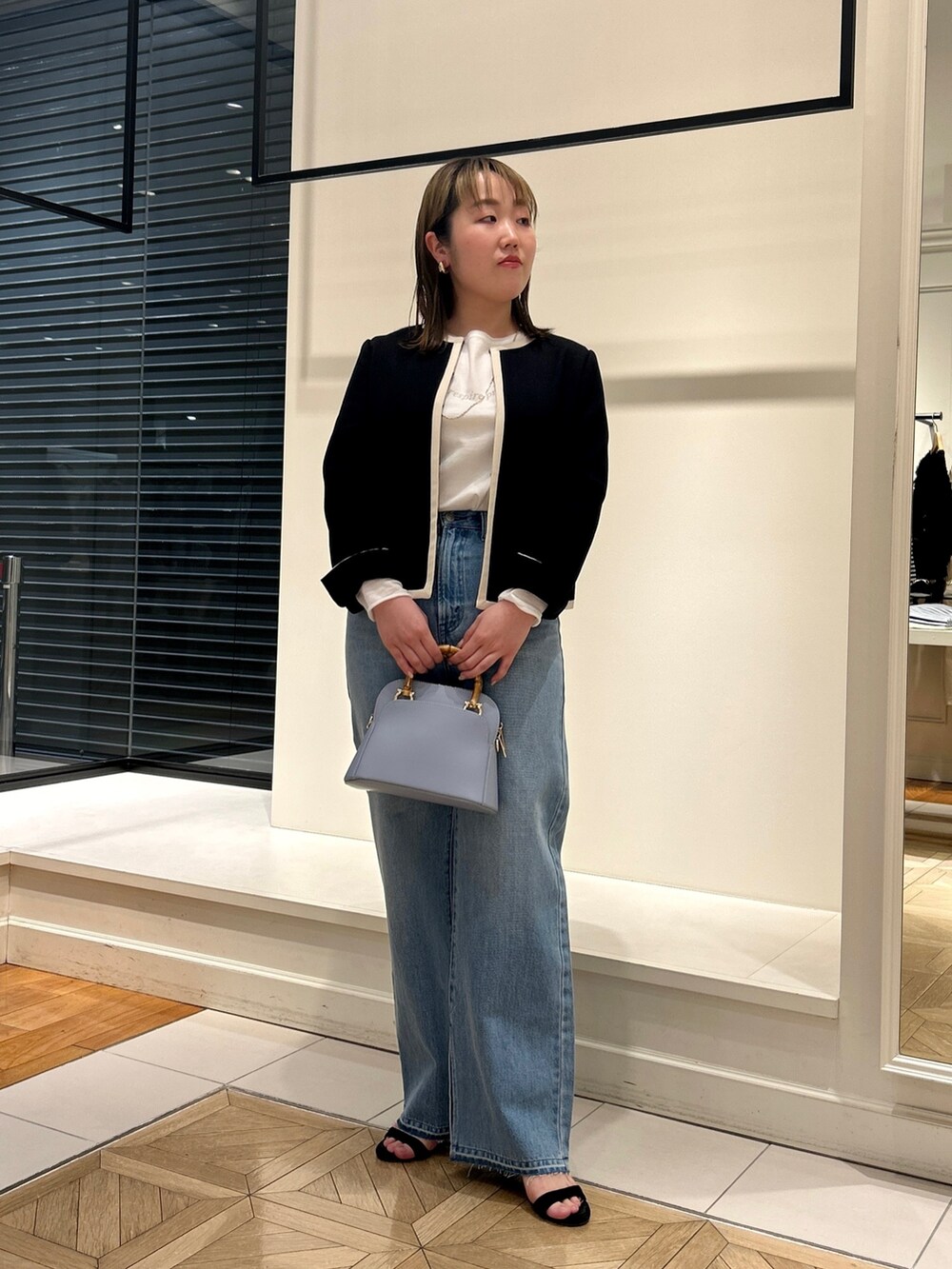 ブラック系のノーカラージャケット、ホワイト系のTシャツ/カットソー、ブルー系のデニムパンツを着用したレディースの冬コーディネートの2枚目の写真