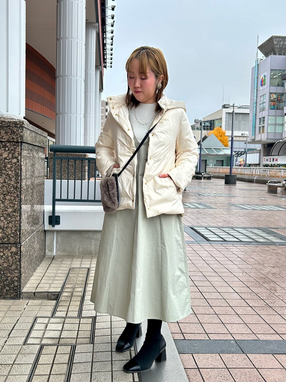 ホワイト系のダウンジャケット/コート、グレー系のワンピース、シルバー系のニット/セーターを着用したレディースの冬コーディネートの2枚目の写真