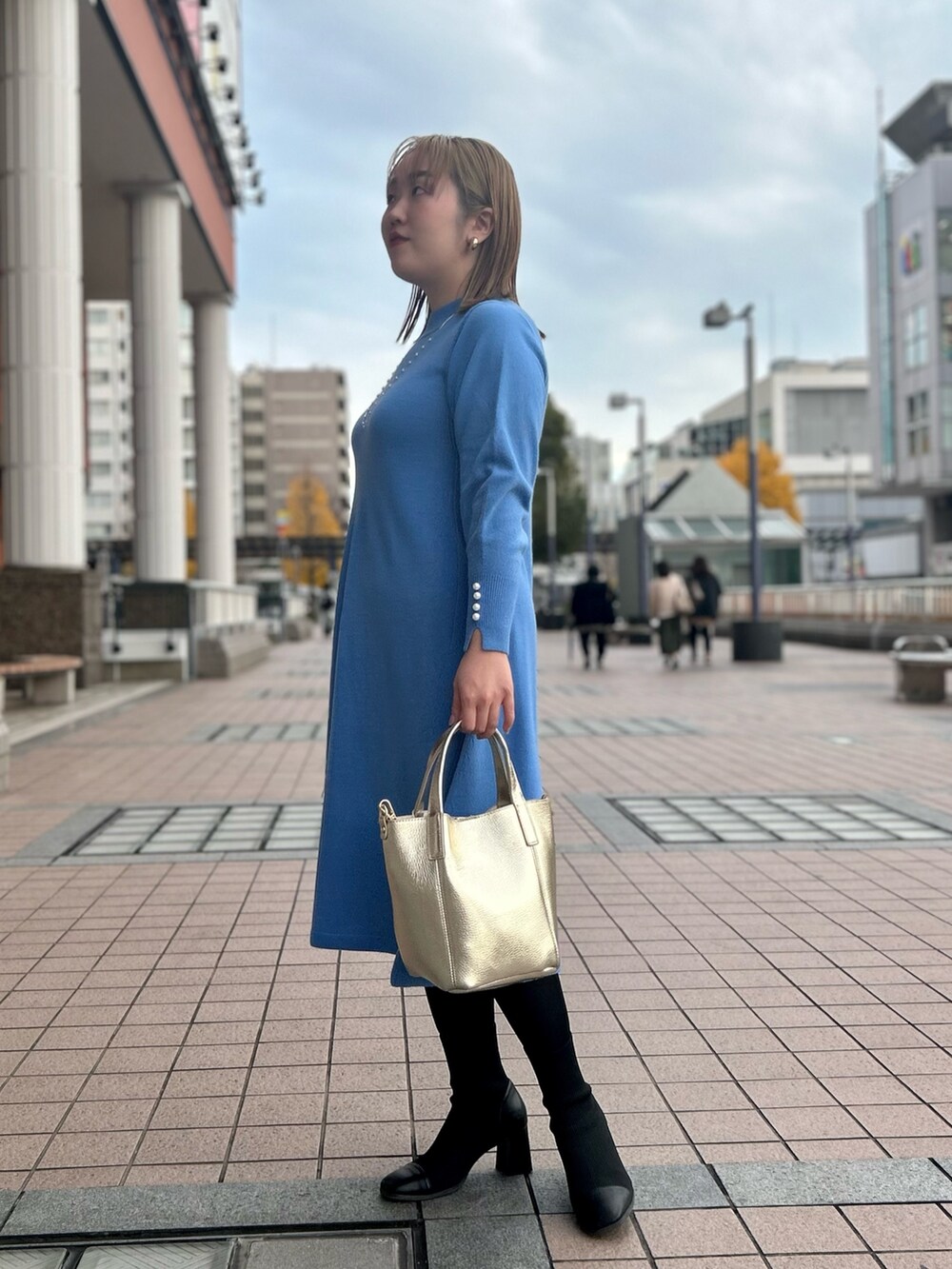 ブルー系のワンピース、ゴールド系のトートバッグ、ゴールド系のイヤリングを着用したレディースの冬コーディネートの3枚目の写真