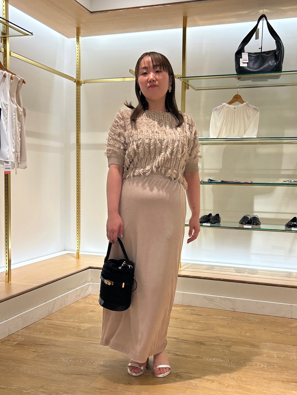 ベージュ系のニット/セーター、ベージュ系のスカート、ブラック系のショルダーバッグを着用したレディースの夏コーディネートの9枚目の写真