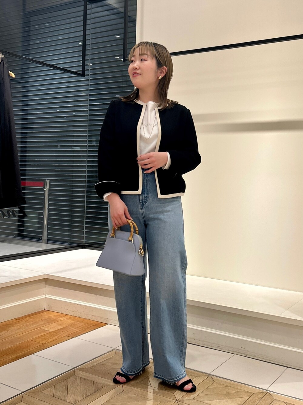 ブラック系のノーカラージャケット、ホワイト系のTシャツ/カットソー、ブルー系のデニムパンツを着用したレディースの冬コーディネートの9枚目の写真