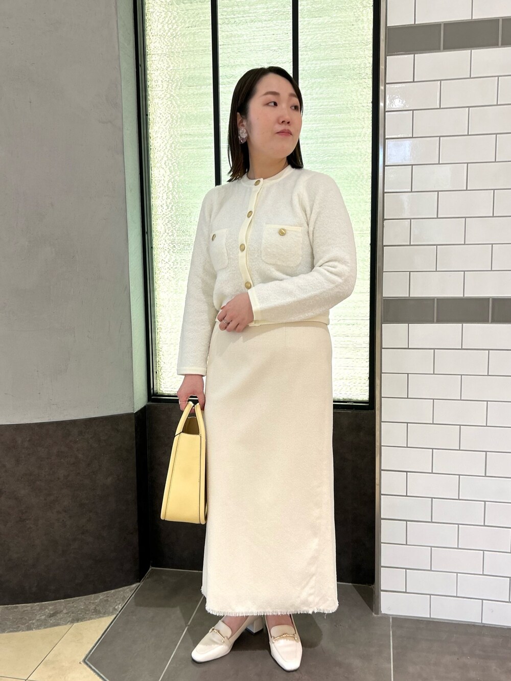 ホワイト系のカーディガン/ボレロ、ホワイト系のスカート、イエロー系のハンドバッグを着用したレディースの秋コーディネートの10枚目の写真