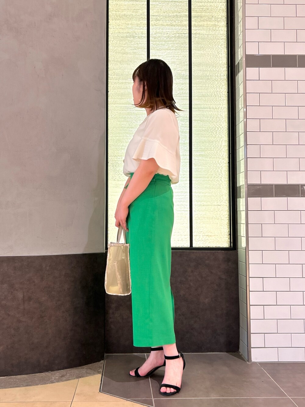 ベージュ系のトートバッグ、ホワイト系のシャツ/ブラウス、グリーン系のスカートを着用したレディースの春コーディネートの3枚目の写真
