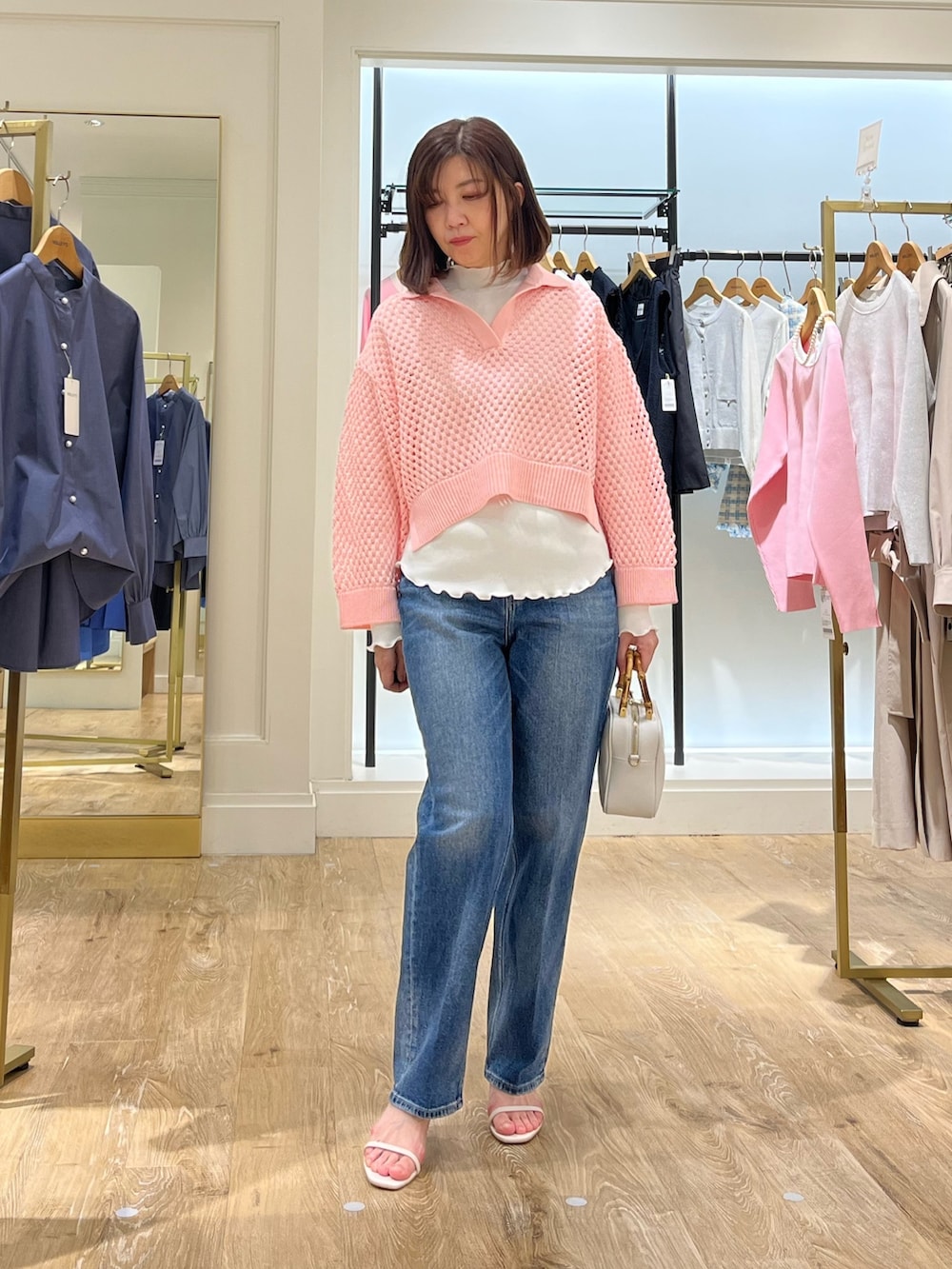 ピンク系のニット/セーター、ホワイト系のTシャツ/カットソー、ブルー系のデニムパンツを着用したレディースの春コーディネートの2枚目の写真