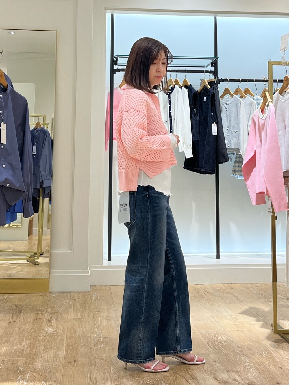 ピンク系のニット/セーター、ホワイト系のTシャツ/カットソー、ブルー系のデニムパンツを着用したレディースの春コーディネートの6枚目の写真