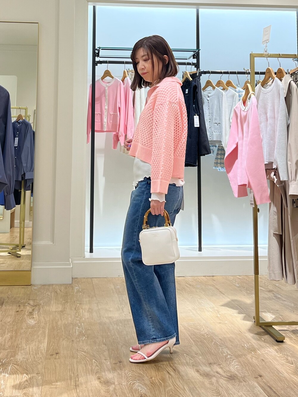 ピンク系のニット/セーター、ホワイト系のTシャツ/カットソー、ブルー系のデニムパンツを着用したレディースの春コーディネートの5枚目の写真