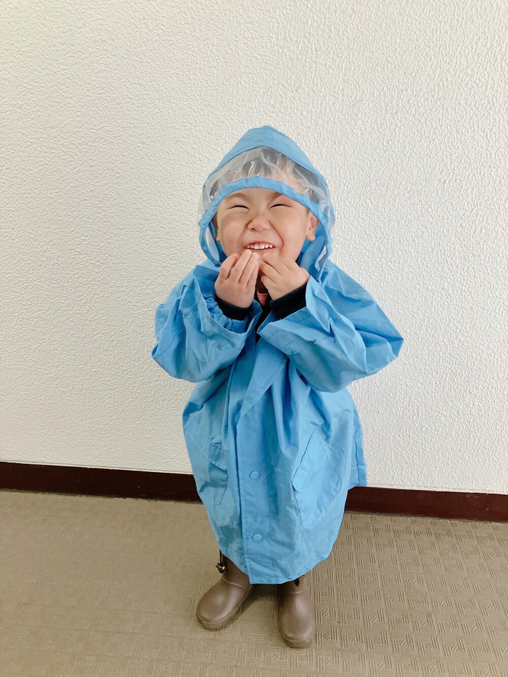 ブルー系のポンチョを着用したキッズの春コーディネートの2枚目の写真