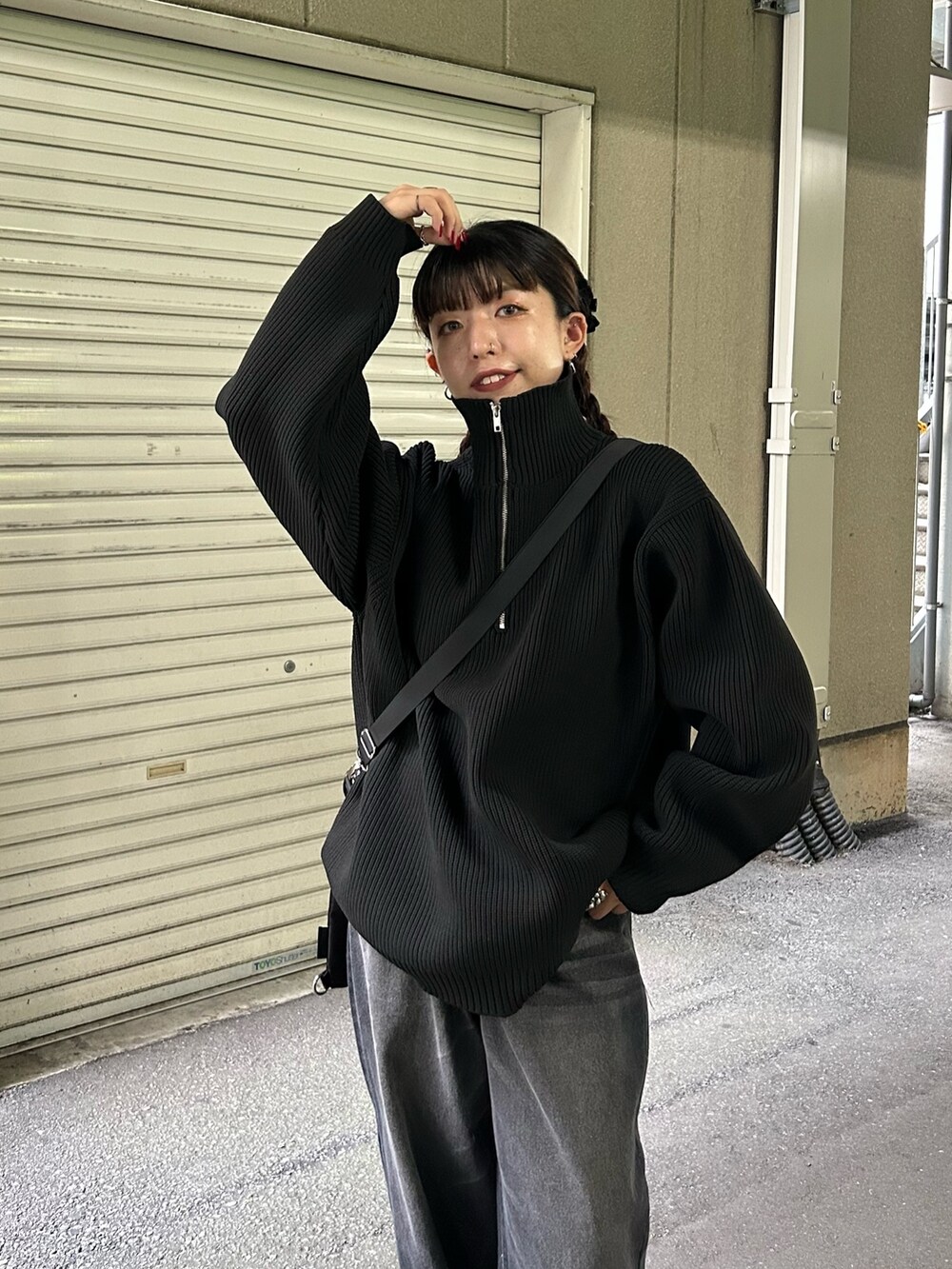 ブラック系のニット/セーター、ブラック系のデニムパンツ、ブラック系のショルダーバッグを着用したレディースの秋コーディネートの2枚目の写真