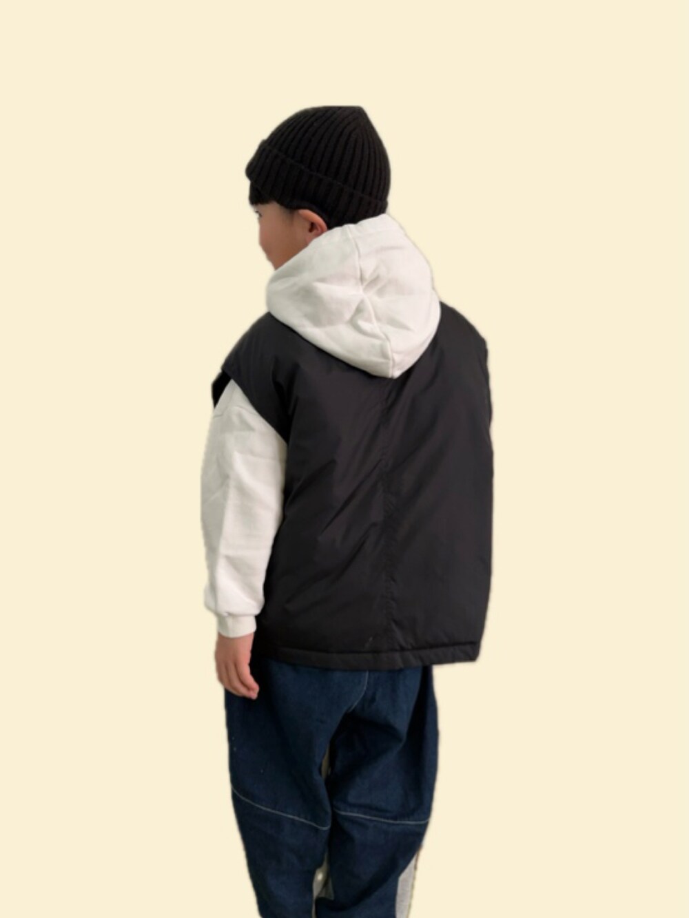 ブラック系のダウンベスト、グレー系のパンツ、ブラック系のニットキャップ/ビーニーを着用したキッズの冬コーディネートの2枚目の写真
