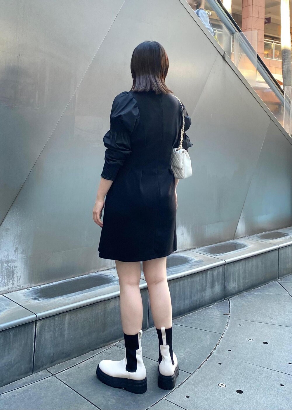 ホワイト系のショルダーバッグ、ホワイト系のブーツ、ブラック系のワンピースを着用したレディースの秋コーディネートの3枚目の写真