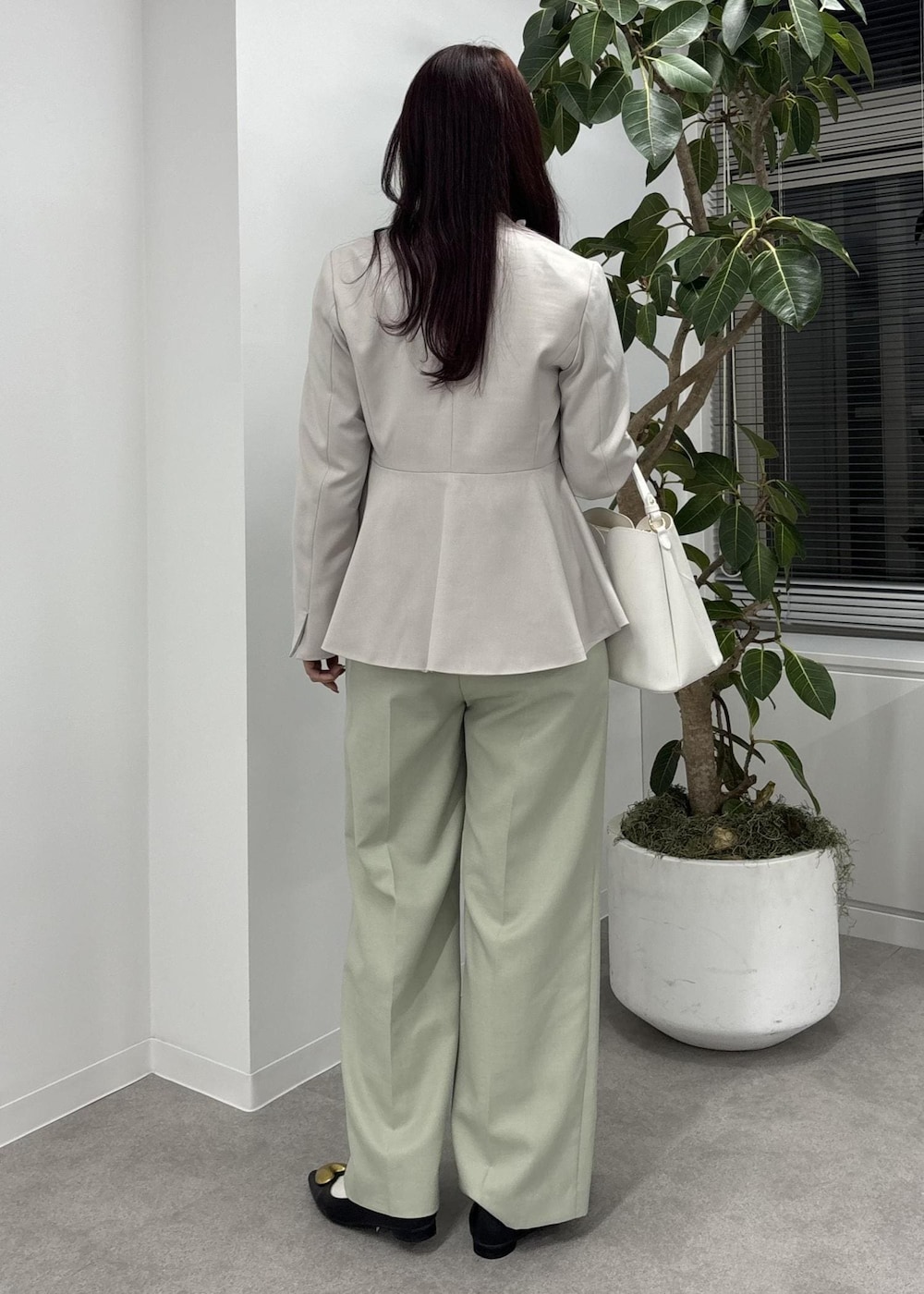 ホワイト系のショルダーバッグ、グリーン系のスラックス、ブラック系のバレエシューズを着用したレディースの冬コーディネートの4枚目の写真