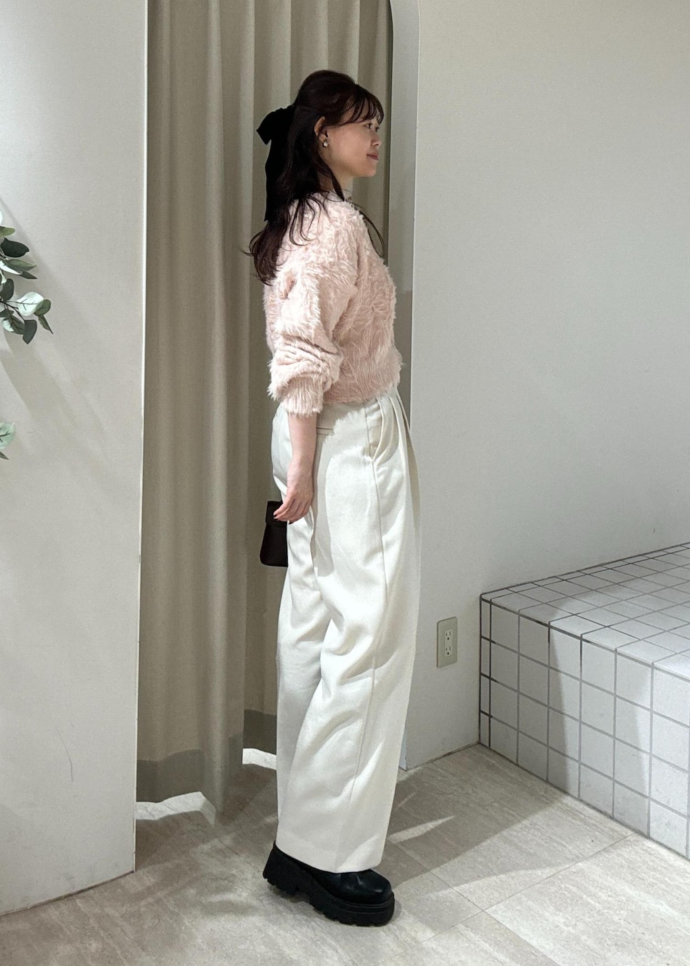 ブラウン系のショルダーバッグ、ブラック系のブーツ、ピンク系のカーディガン/ボレロを着用したレディースの冬コーディネートの3枚目の写真