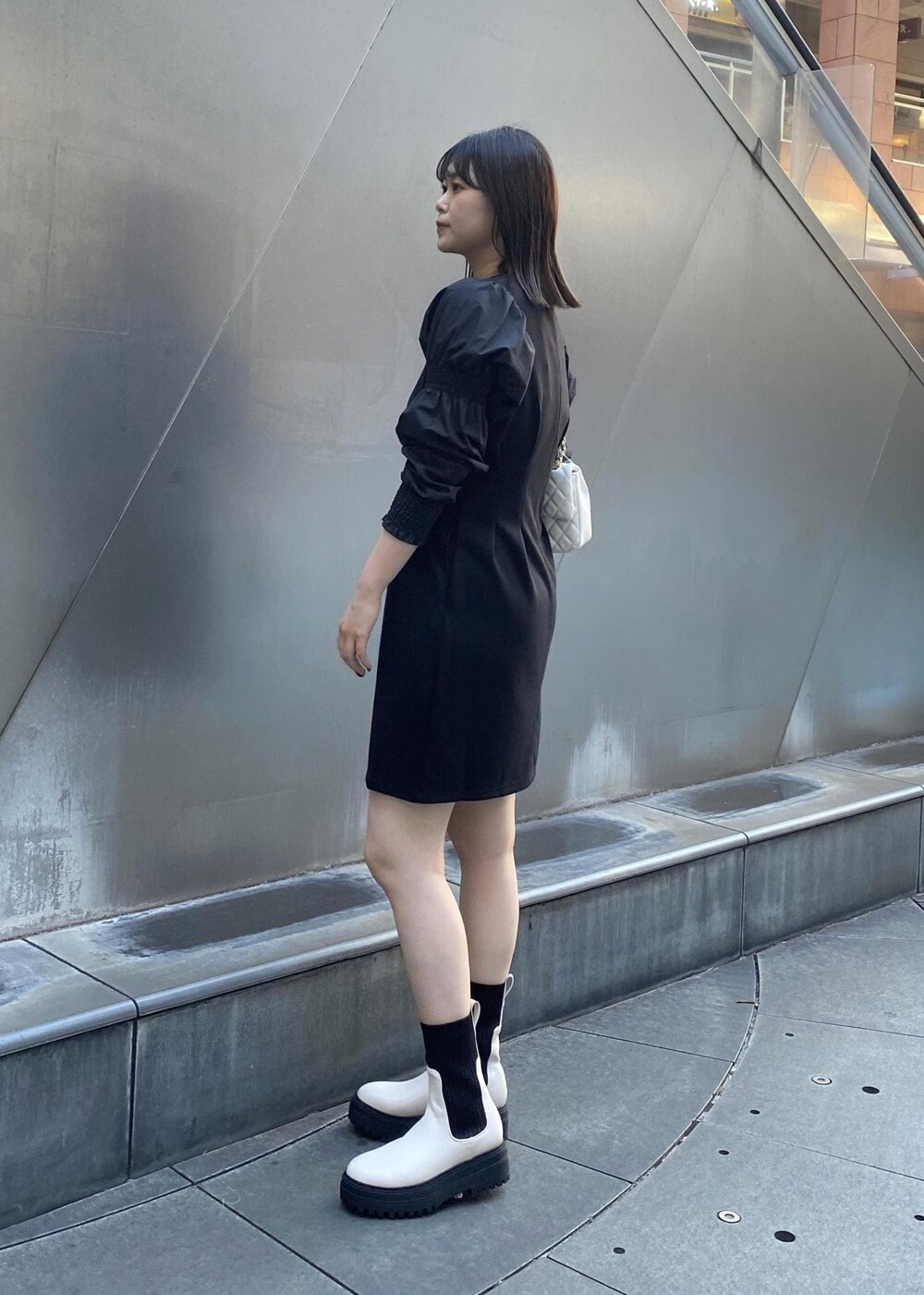 ホワイト系のショルダーバッグ、ホワイト系のブーツ、ブラック系のワンピースを着用したレディースの秋コーディネートの4枚目の写真