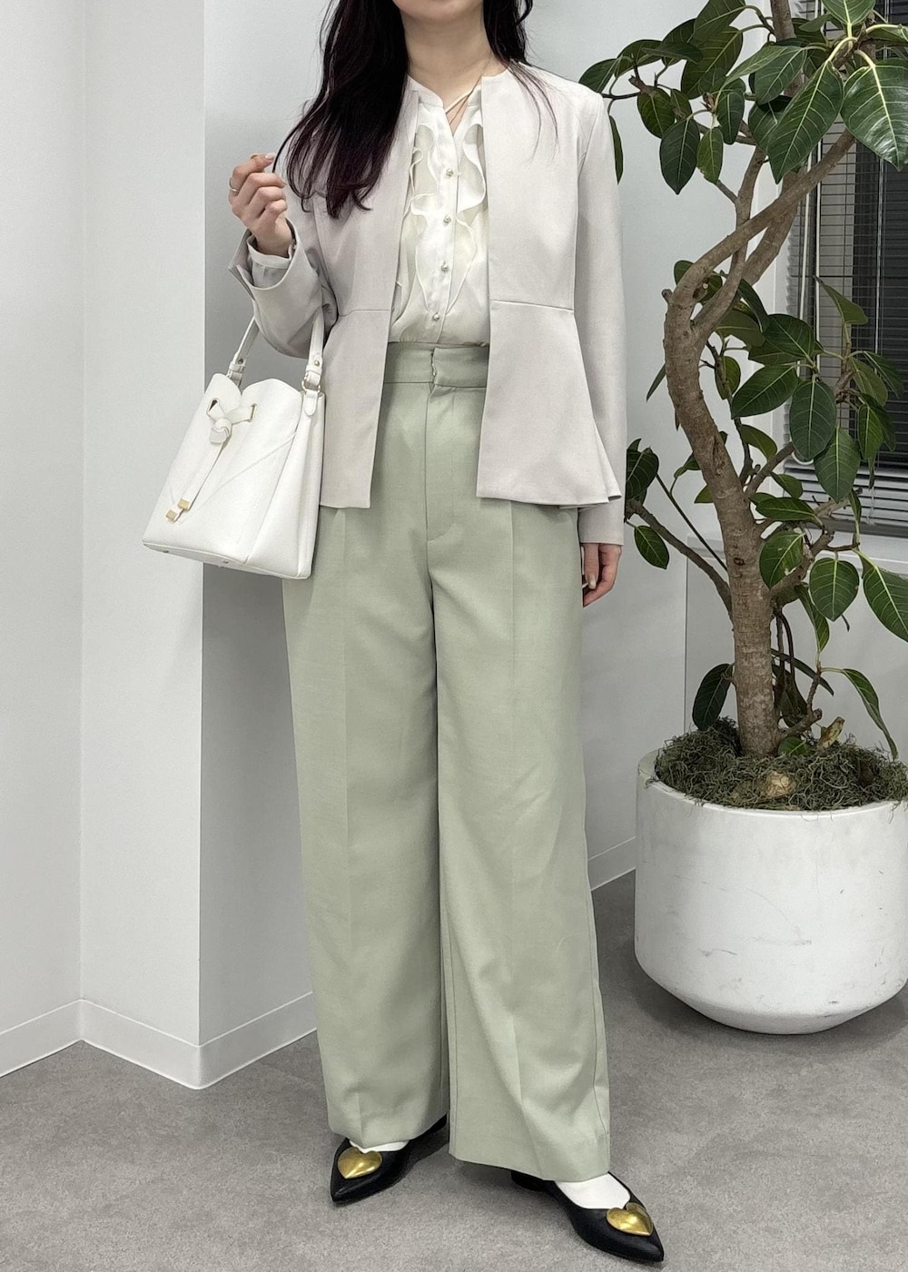 ホワイト系のショルダーバッグ、グリーン系のスラックス、ブラック系のバレエシューズを着用したレディースの冬コーディネートの2枚目の写真