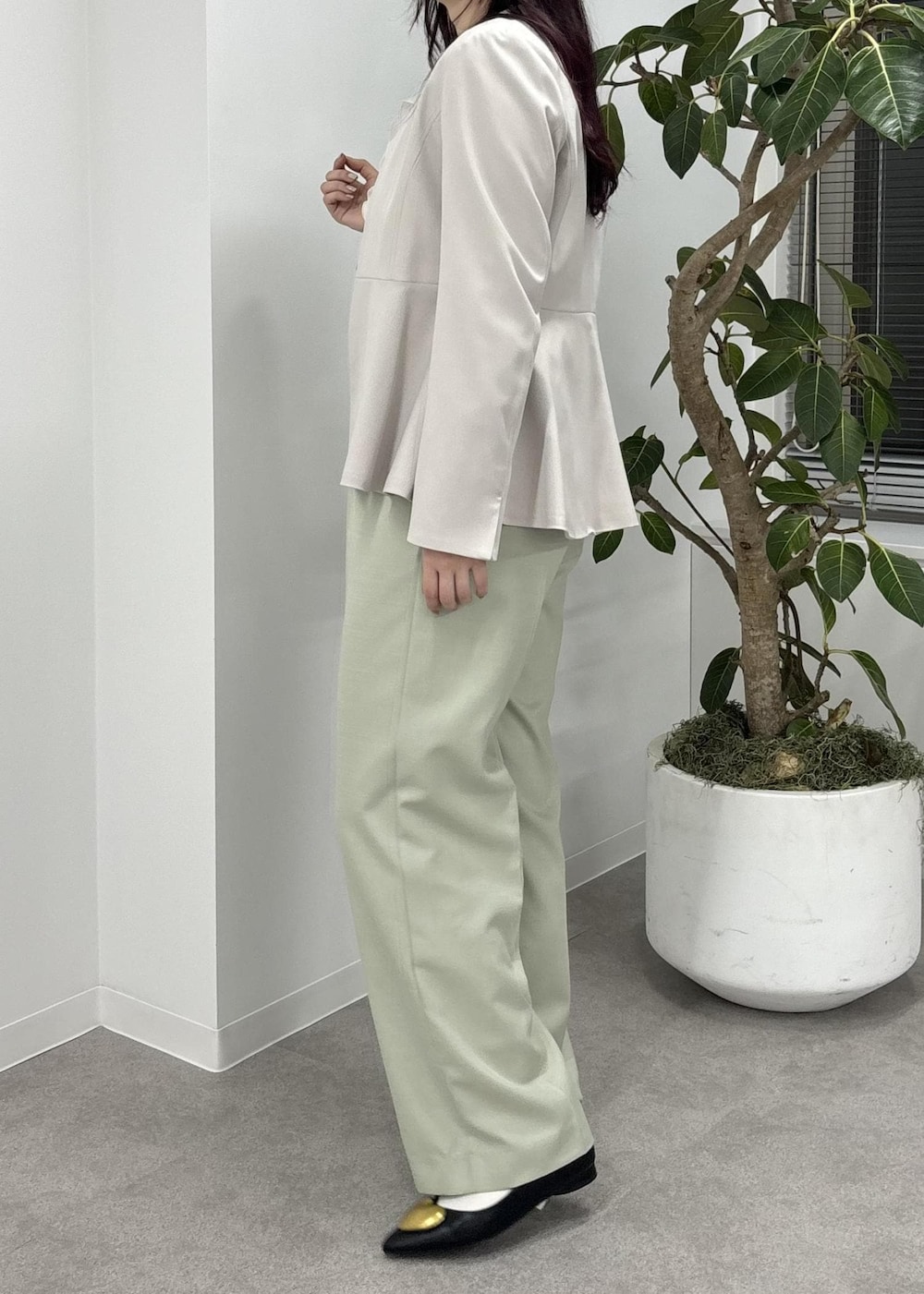 ホワイト系のショルダーバッグ、グリーン系のスラックス、ブラック系のバレエシューズを着用したレディースの冬コーディネートの3枚目の写真