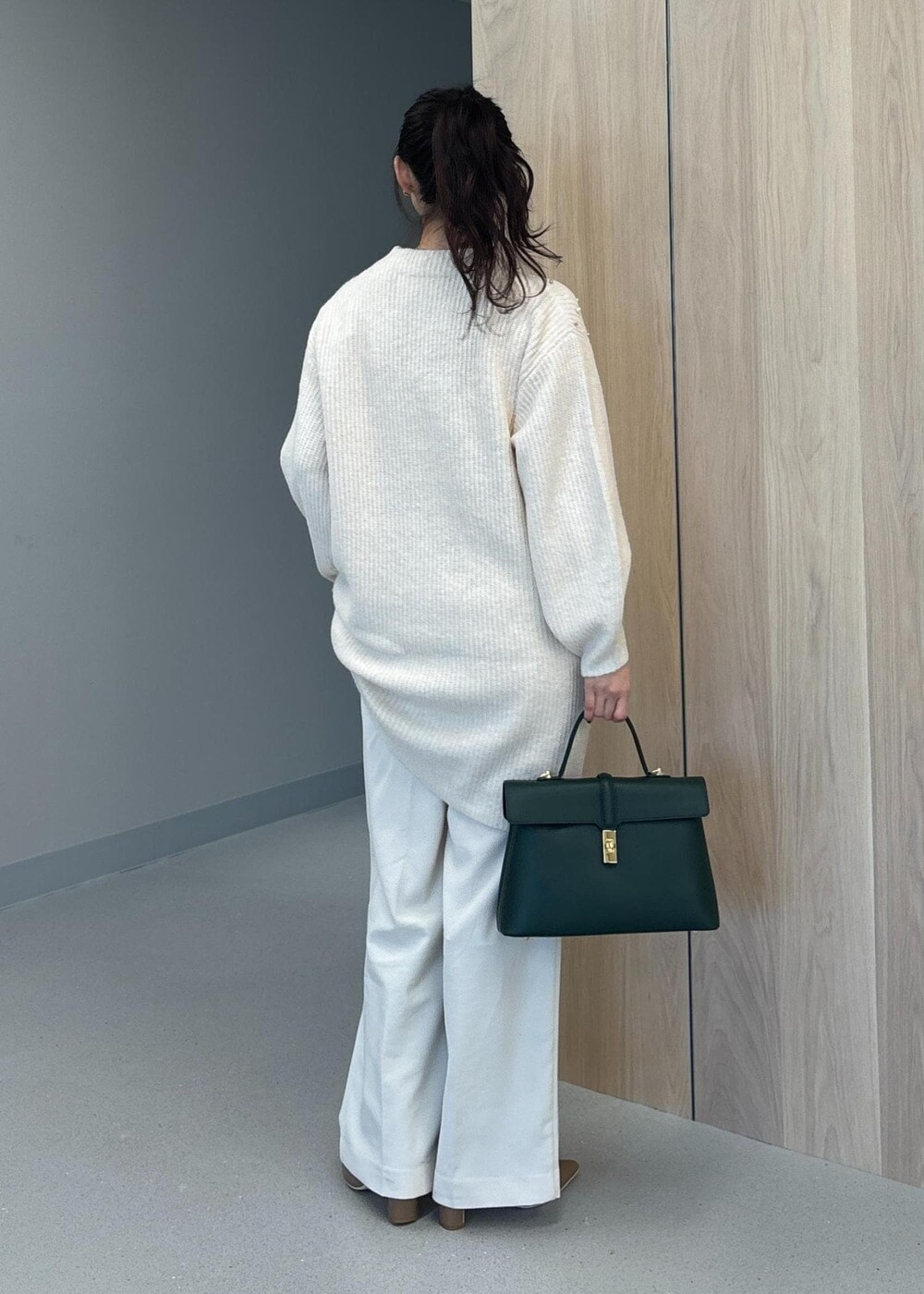 グリーン系のハンドバッグ、ベージュ系のブーツ、ホワイト系のワンピースを着用したレディースの冬コーディネートの4枚目の写真