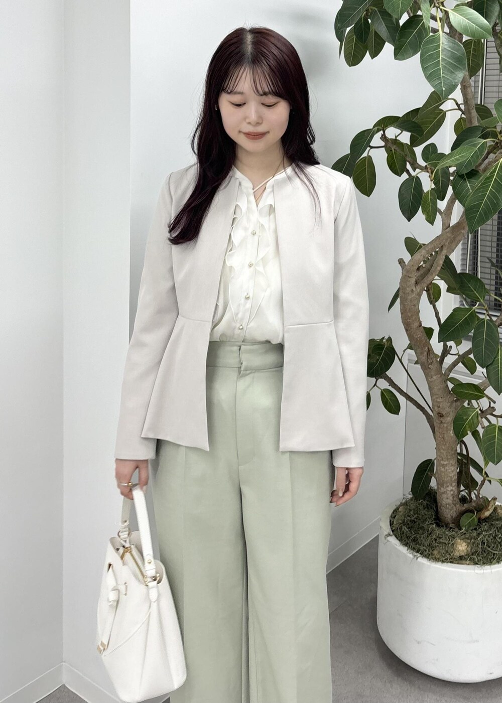 ホワイト系のショルダーバッグ、グリーン系のスラックス、ブラック系のバレエシューズを着用したレディースの冬コーディネートの6枚目の写真