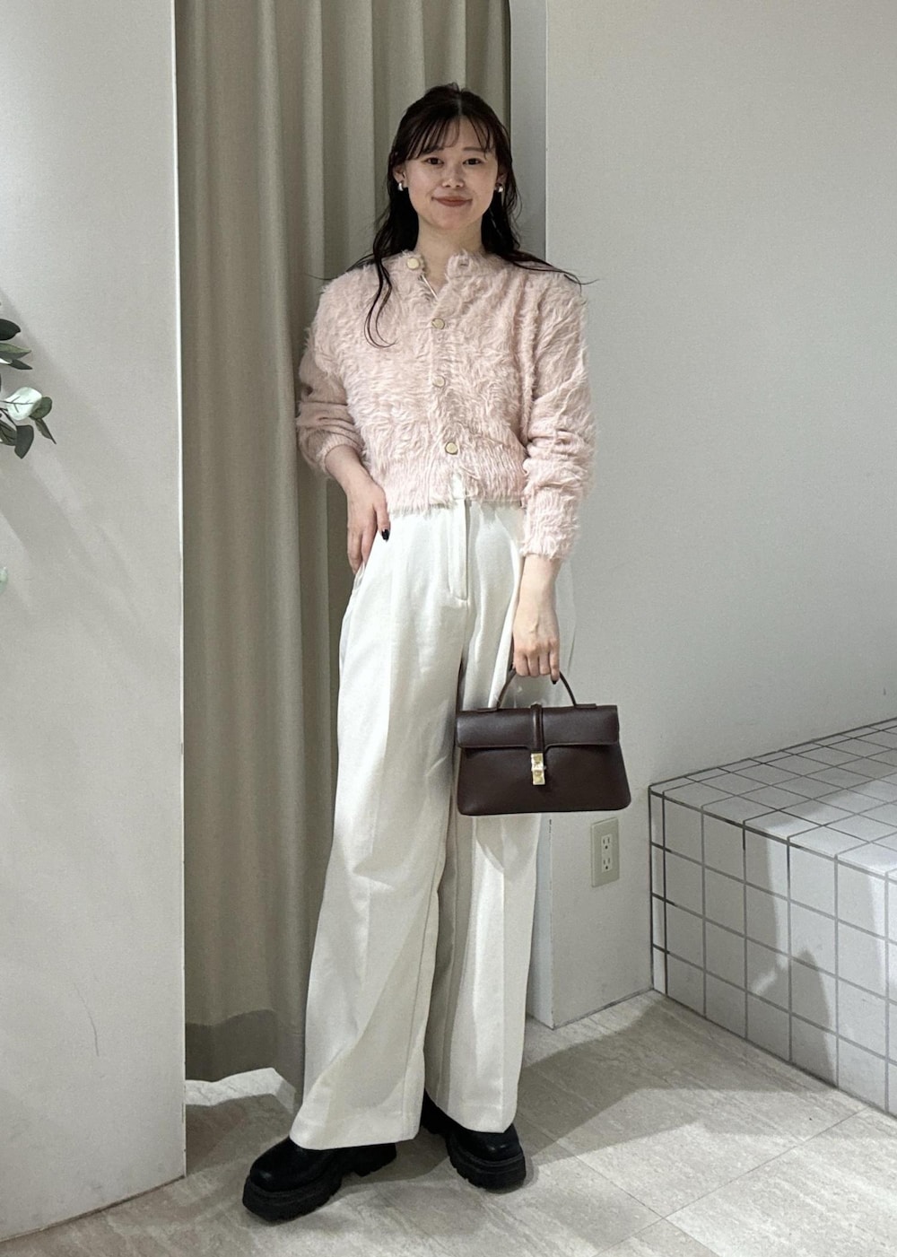 ブラウン系のショルダーバッグ、ブラック系のブーツ、ピンク系のカーディガン/ボレロを着用したレディースの冬コーディネートの2枚目の写真