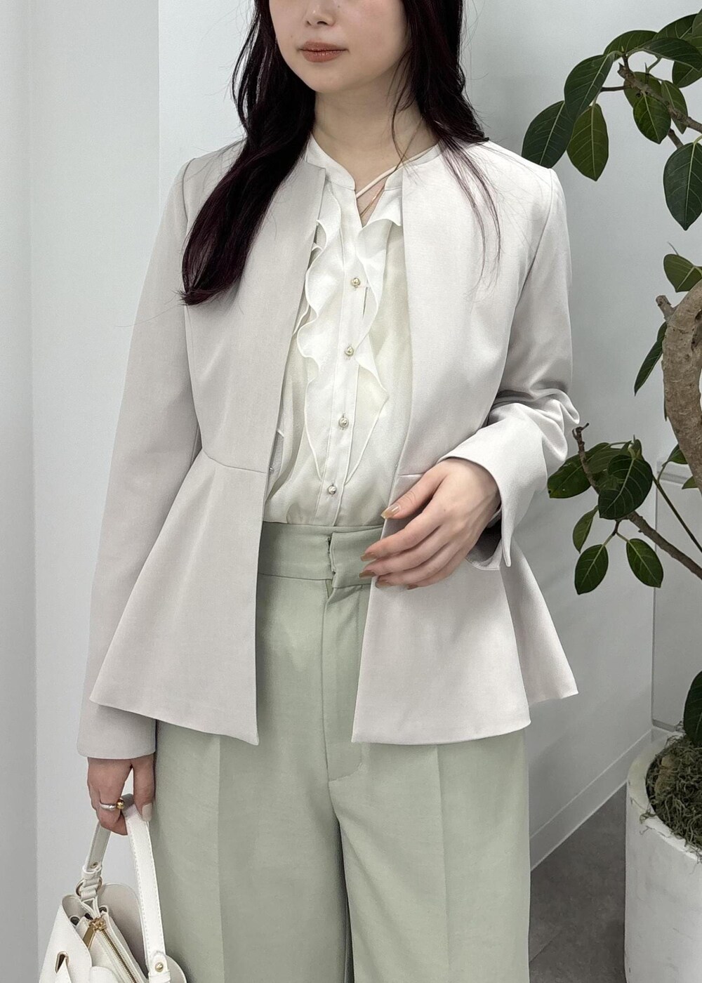 ホワイト系のショルダーバッグ、グリーン系のスラックス、ブラック系のバレエシューズを着用したレディースの冬コーディネートの7枚目の写真