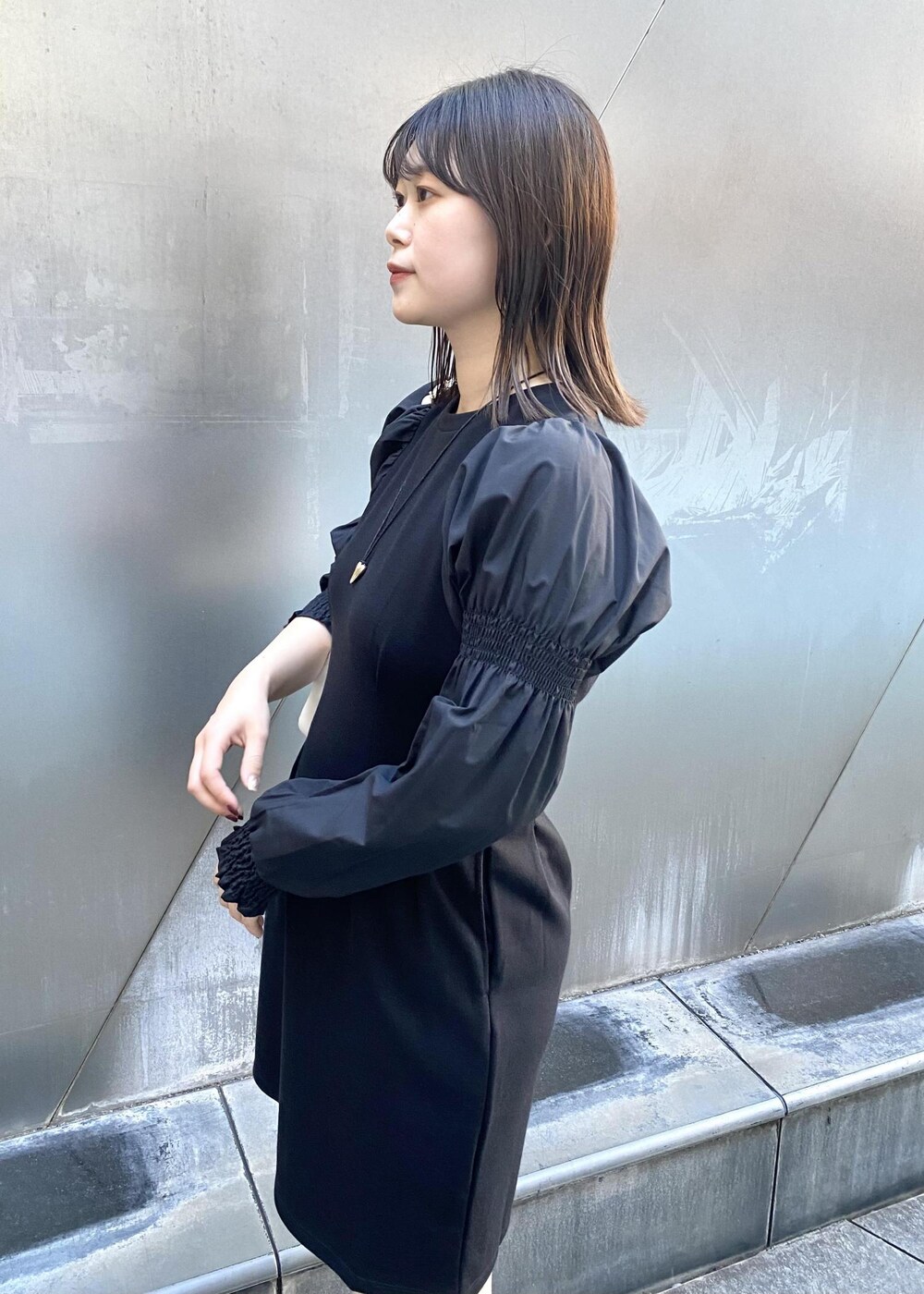 ホワイト系のショルダーバッグ、ホワイト系のブーツ、ブラック系のワンピースを着用したレディースの秋コーディネートの5枚目の写真