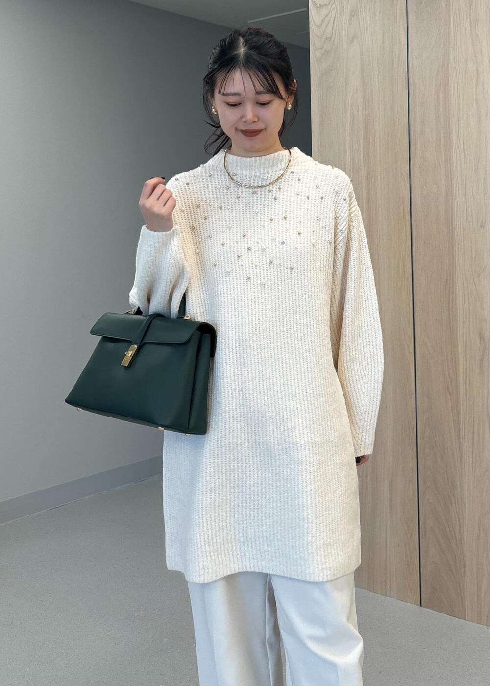 グリーン系のハンドバッグ、ベージュ系のブーツ、ホワイト系のワンピースを着用したレディースの冬コーディネートの7枚目の写真