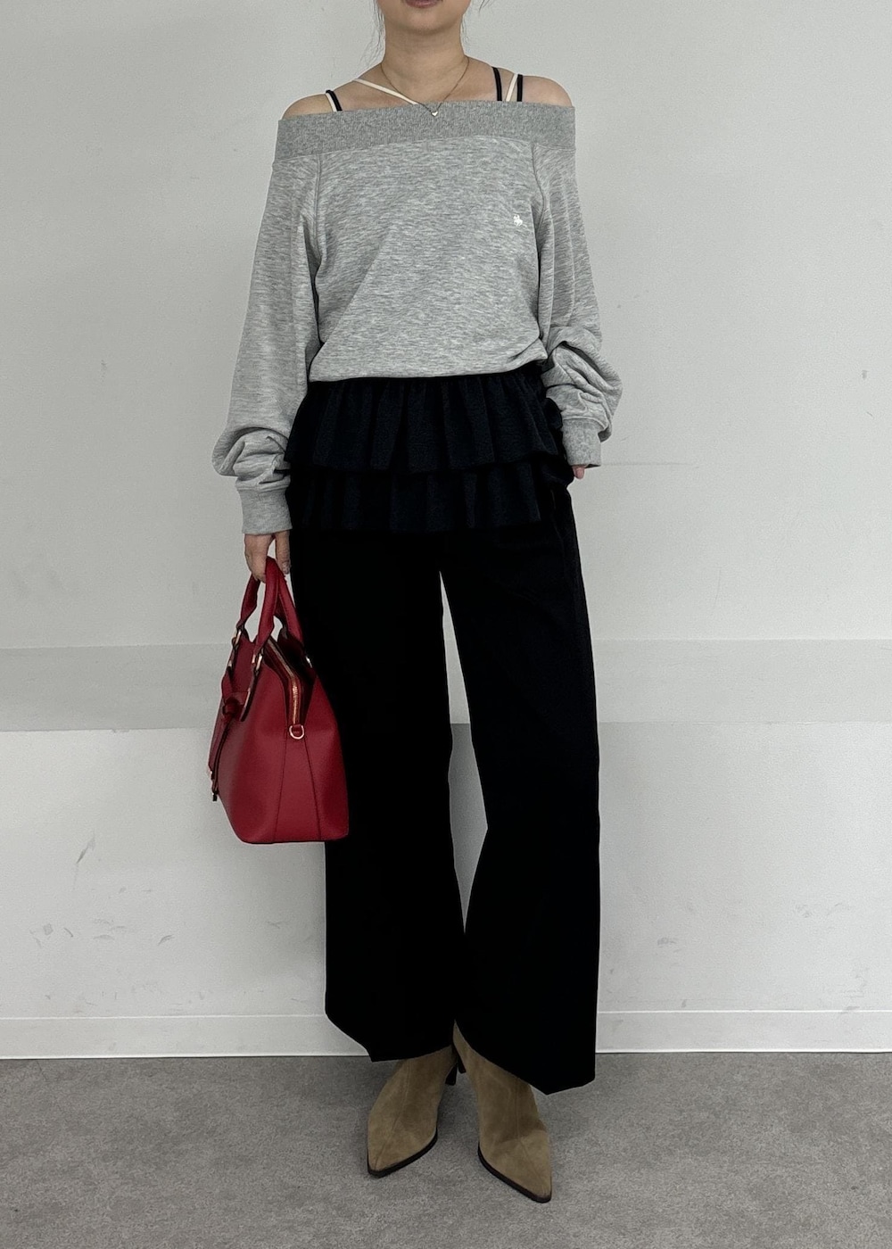レッド系のボストンバッグ、ブラック系のキャミソール、グレー系のスウェットを着用したレディースの秋コーディネートの3枚目の写真