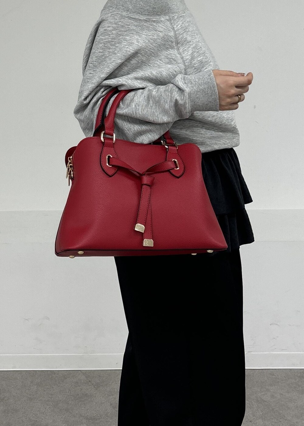 レッド系のボストンバッグ、ブラック系のキャミソール、グレー系のスウェットを着用したレディースの秋コーディネートの7枚目の写真