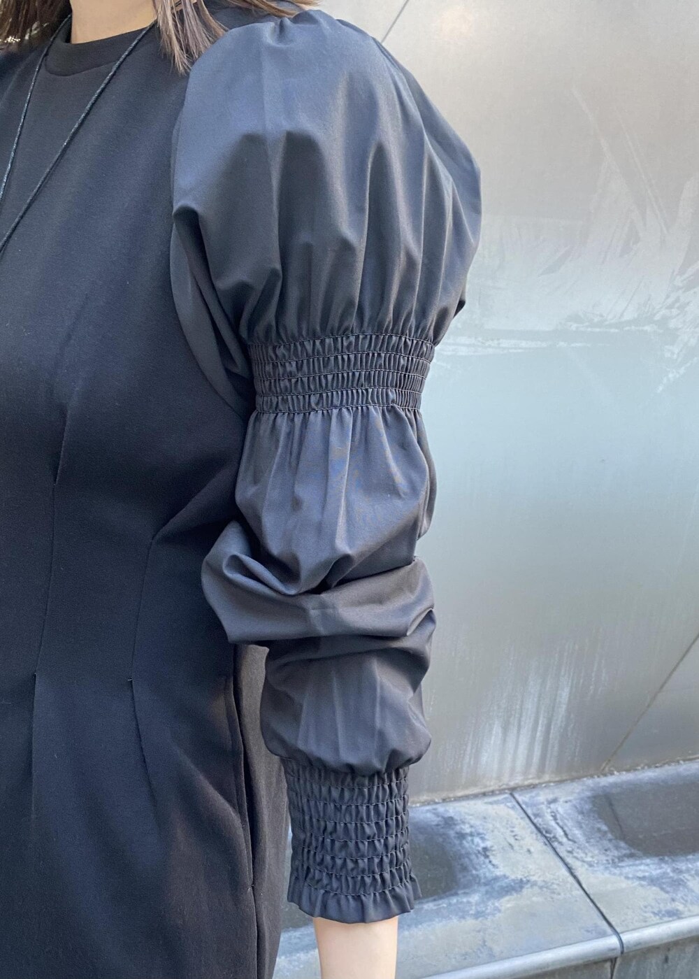 ホワイト系のショルダーバッグ、ホワイト系のブーツ、ブラック系のワンピースを着用したレディースの秋コーディネートの6枚目の写真