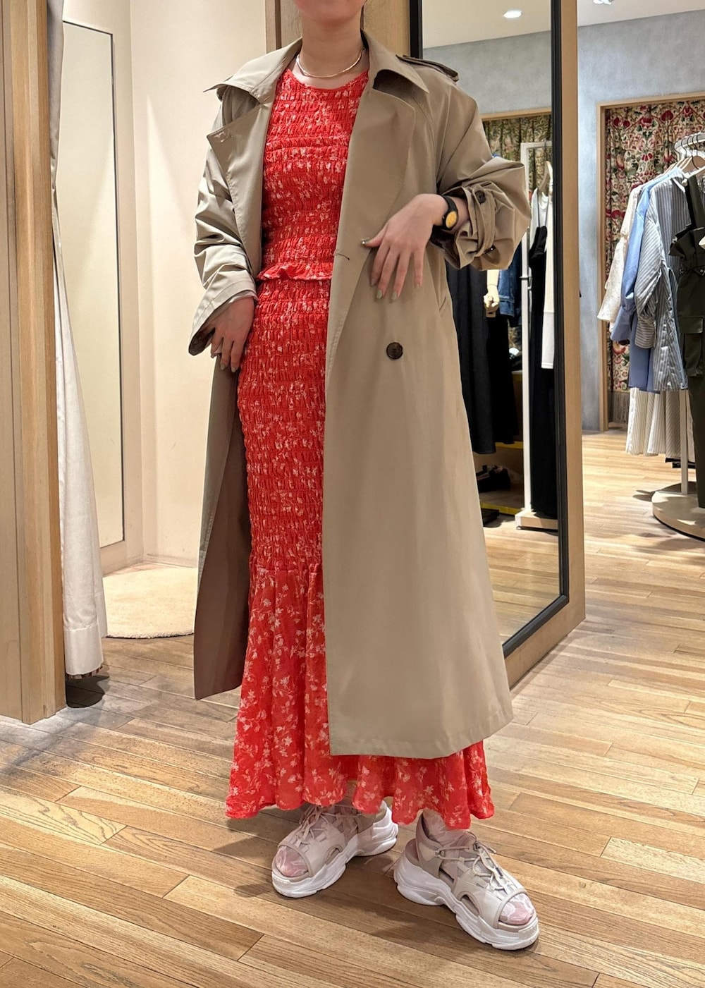 ベージュ系のトレンチコート、ベージュ系のサンダル、オレンジ系のスカートを着用したレディースの春コーディネートの2枚目の写真